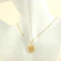 Nahaufnahme des goldenen Sonnenanhängers mit Spiralmuster auf einem weißen Mannequin - Gold