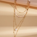 Détail d'un collier multicouche doré avec des perles blanches et un pendentif goutte - Doré