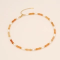 Bamboo style natural stone necklace with pearls and gold beads on a beige surface - Orange Stone
