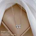 Close-up of bow necklace on silk background showing size 1.2x0.9cm and 2.5g weight - Bowknot Necklace (N128) / Silver