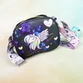 Detail of unicorn crossbody bag showing galaxy print with pink hearts and wide woven strap - Black