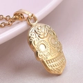 Macro shot of 18k gold plated sugar skull pendant with floral relief on pink silk - Necklace Set / Gold