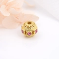 Makro-Detail einer 18k vergoldeten Hohlperle mit rosa Zirkon für DIY-Schmuckstücke - Gold mit rosa Zirkon