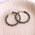 Detailed view of gold hoop earrings wrapped in black leather with printed white lettering - Silver Earring Post - Gold - Black