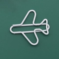 White airplane shaped creative metal paper clip on a vibrant green background - White