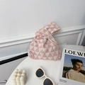 Close-up of pink and white geometric triangle knit wrist bag with minimalist accessories - Pink Triangle