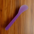 Single purple plastic facial mask spatula on a dark wood texture background - Pack of 100 / Transparent Purple