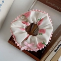 Detail von flauschigem beigem Haargummi mit Erdbeermuster und rosa Pompons - Erdbeer Spitzen Scrunchie