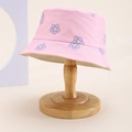 Close-up of pink cotton kids bucket hat with purple smile flower patterns on wood stand - Kids One Size / Pink (Smile Flower Print)