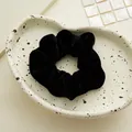 Primo piano di un elastico per capelli in velluto nero su un piatto di ceramica bianca - Velluto Nero