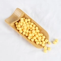 Bright yellow PVC decorative grains and wax beads displayed on a small bamboo shovel - Peas (500g)