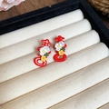 Gros plan sur des boucles d'oreilles rouges Xi avec détails floraux blancs et jaunes - Boucles d'oreilles fleur caractère Xi rouge et blanc