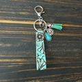 Detail of western leather keychain with turquoise stones and sunflower charm on wood - Turquoise Sunflower Tassel