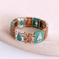 Detail eines Vintage-Perlenarmbands mit Schnitzmustern auf rosa Stoffhintergrund - Gold/Silber/Grün/Bronze Gespleißt