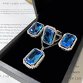 Three-piece jewelry set with emerald-cut blue gemstones in a black display case - Rectangular Blue Diamond Stud Earrings Tz-34