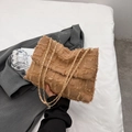 Braune strukturierte Umhängetasche mit Fransen und Goldkette, von einer Hand gehalten - Khaki
