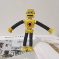 Dettaglio del robot giocattolo giallo con ventose e tubi telescopici su una rivista - Senza Luce / Giallo