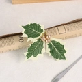 Detail of Christmas napkin ring with artificial holly leaves and gold berries on vintage paper - Gold Berry Christmas Leaf
