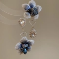 Detalle de pendientes largos de flores con bordado azul y grandes cristales color champán - Marrón