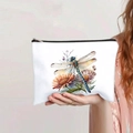 Detail of white makeup bag with colorful dragonfly and flower prints held by a model - Colored Dragonfly Floral Watercolor Style (131-3)