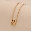 Detailed view of golden initial R pendant necklace with sparkling pavé crystal settings - Letter R