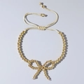 Bracelet élégant à perles plaqué or 18K avec nœud papillon et cordon tressé crème réglable - Nœud Entièrement en Perles Dorées