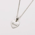 Macro de un colgante de corazón plateado con el detalle del texto Blessed grabado - Plata Blessed