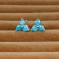 Macro shot of silver clover stud earrings featuring round turquoise stones on velvet tray - Silver/Blue Zirconia