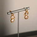 Elegante gouden druppeloorbellen met fonkelende kristallen op een luxe displaystand - Stijl 2 (Gouden drievoudige zirkonia hangende oorbellen)