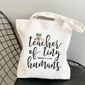 White canvas tote bag featuring teacher of tiny humans print and colorful books - Teacher of Tiny Humans