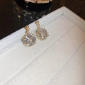 Macro shot of gold plated floral earrings with clear zircon stones on a beige velvet tray - Gold Geometric Flower Radiant