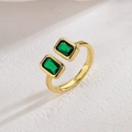 Bague ouverte géométrique dorée avec deux zircons verts sur une surface en pierre - Style C