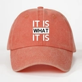 Detailed close-up of 'IT IS WHAT IT IS' text printed on a washed coral baseball cap - One Size(Adjustable) / Washed Orange