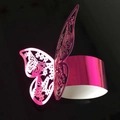 Pink laser-cut butterfly napkin ring with metallic luster on a black background - Reflective Rose Red