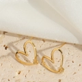 Dettaglio orecchini a cuore dorati su sfondo in seta crema e pietra naturale - Cuore