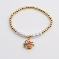 Detalle de pulsera de cuentas doradas con perlas y colgante de campana de esmalte rojo - Estilo de Campana con Lazo