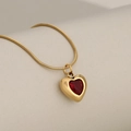 Elegant gold snake chain necklace with a ruby red heart pendant on a white pedestal - Gold + Red Zirconia