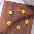 Detalle de pulsera dorada con dijes circulares grabados con rayos de sol sobre madera - Pulsera con Dijes Redondos
