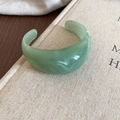Detail showing a light green resin C-shape cuff bracelet with marble texture and open design - Green