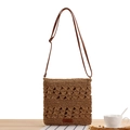 Borsa a tracolla in paglia intrecciata marrone con cinturino in pelle su tavolo in legno - Cammello