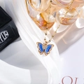 Detail of butterfly necklace pendant with deep blue crystals and micro zircon inlay - Medium Blue & White
