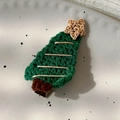 Detail of hand-knitted green wool Christmas tree hair clip with gold thread on ceramic tray - 24450E Meteor Christmas Tree Duckbill Clip