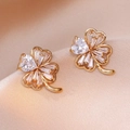 Macro shot of gold four-leaf clover earrings with zircon hearts on champagne satin - Four-Leaf Clover Heart Zirconia Style (E0871)