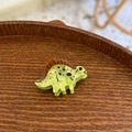 Détail de la pince à cheveux dinosaure en acétate vert sur plateau en bois - Mini Dinosaure Vert