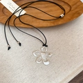 Dettaglio del ciondolo a fiore d'argento con cuore su cordino nero regolabile - Cordino Nero + Fiore Argentato