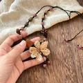 Ethnic handmade necklace with brown wood beads and cream woven flower pendant - Purple Raffia Flower