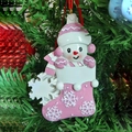Detail of pink resin snowman in Christmas stocking hanging on an evergreen tree branch - Pink