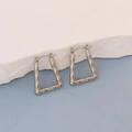 Detailed view of silver oval earrings with bamboo texture on a white stone background - Silver Trapezoid Bamboo Texture