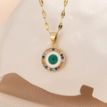 Macro detail of gold evil eye pendant with colorful zircons on white stone base - Gold Colorful Zirconia Green Eye