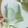 Detail of floral canvas tote bag with a white woven label on a clean desk - Green Background Pink White Floral
